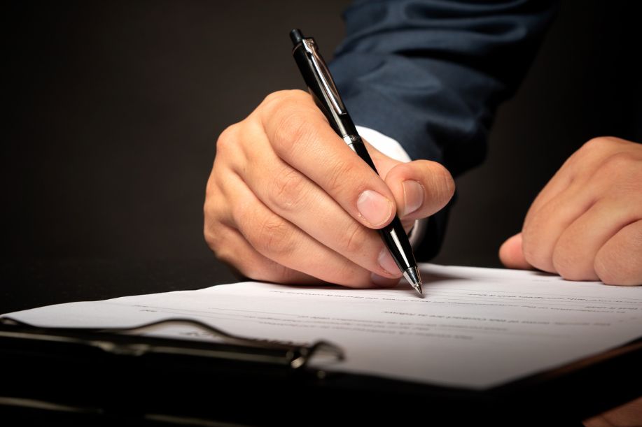 Persona profesional del ramo firmando un documento. Sólo se aprecian las manos, el bolígrafo y el documento.